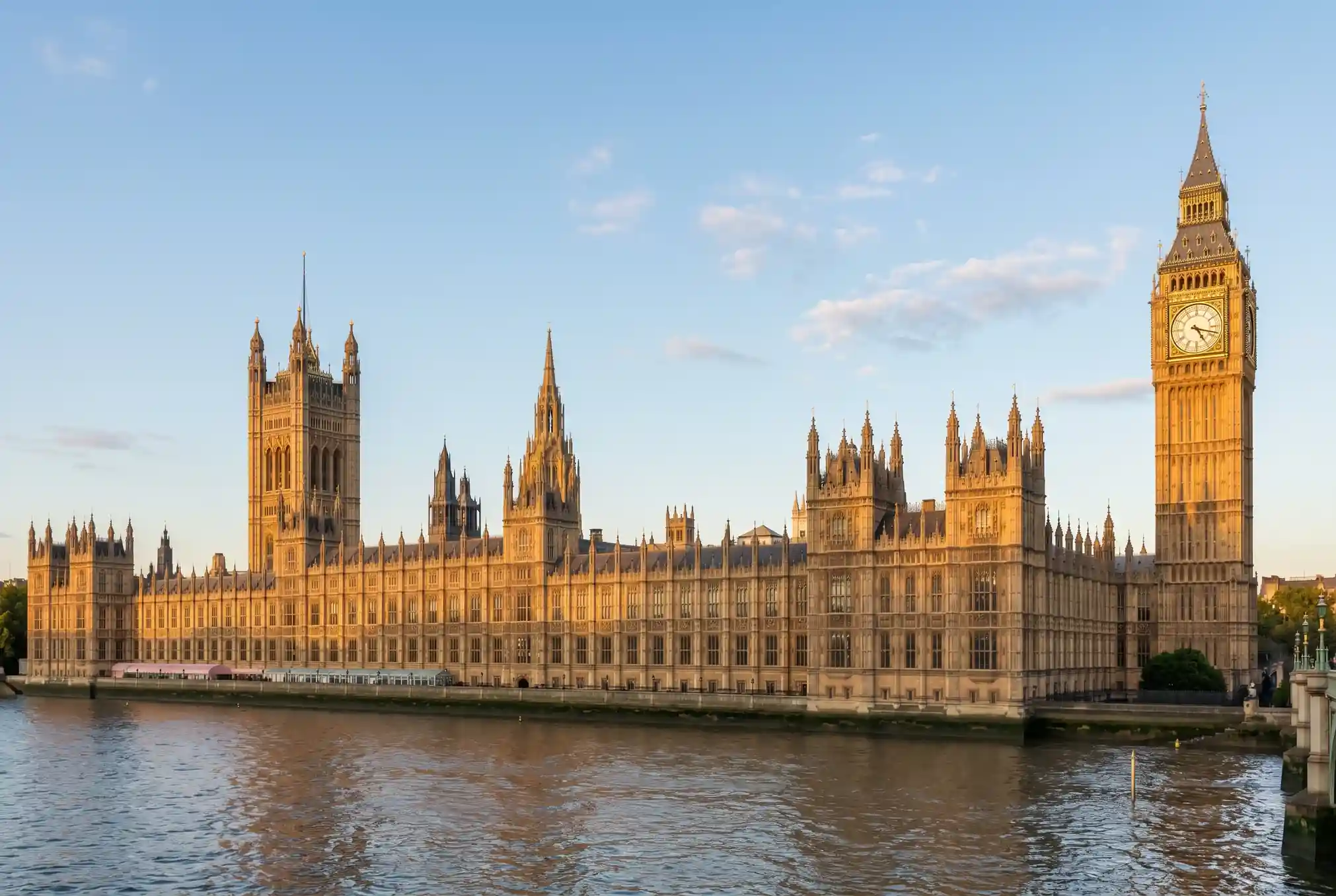 Editorial photograph of the UK Houses of Parliament with a softly lit document on a wooden desk in the foreground